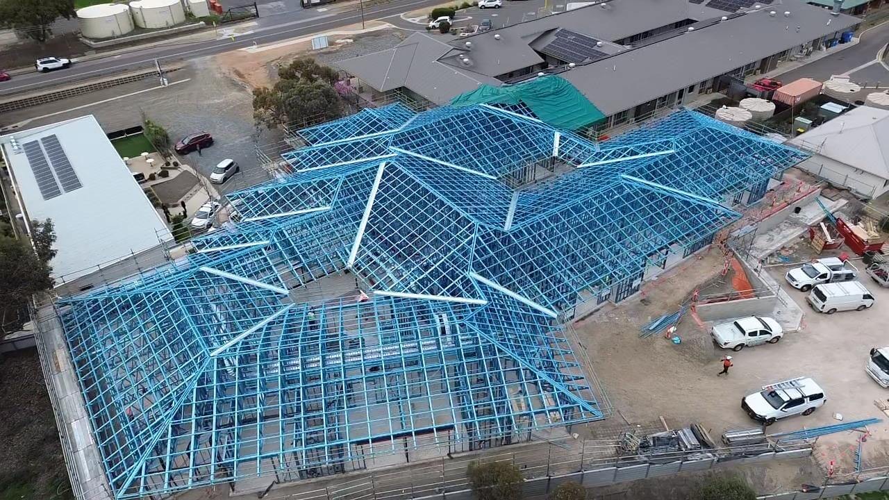 Aerial view of a completed light-gauge steel roof structure spanning a building on site, framed by MYT Framing Solutions
