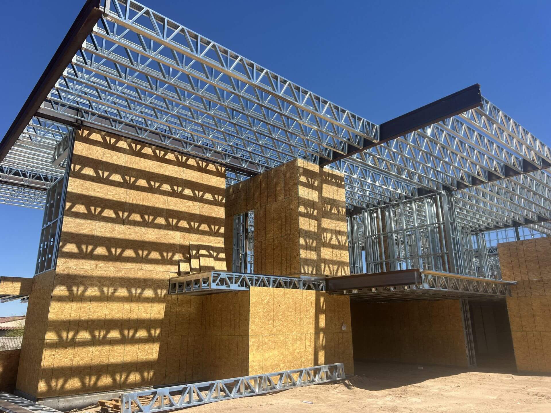 The Young Residence in Arizona standing in light-gauge steel — roof trusses and sheathing in place on the hybrid two-storey structure